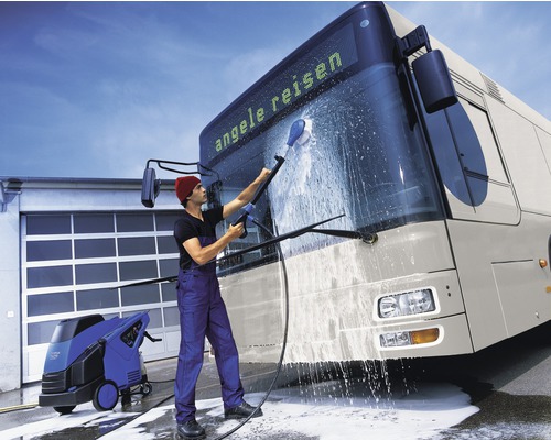 Ein Mann reinigt einen Bus mit einem Hochdruckreiniger