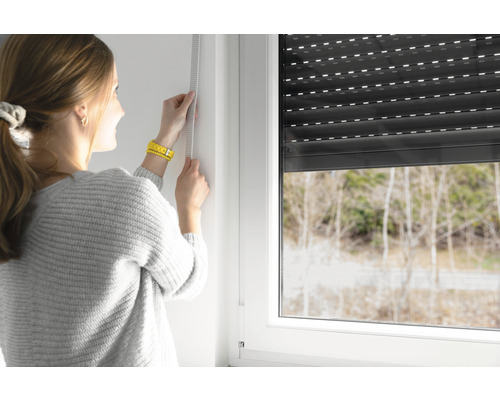Frau misst Fenster für Rollladenmontage