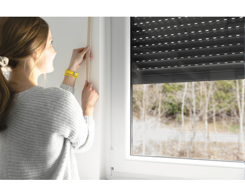 Femme mesurant une fenêtre pour le montage d''un volet roulant