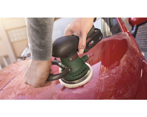 Une personne polit une voiture rouge avec une polisseuse sans fil Bosch