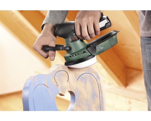 Un homme ponce une chaise en bois avec une ponceuse excentrique Bosch