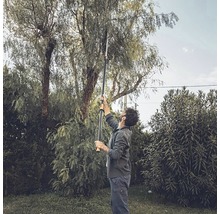 Une personne utilise un ébrancheur télescopique dans le jardin pour couper les branches d''un arbre.