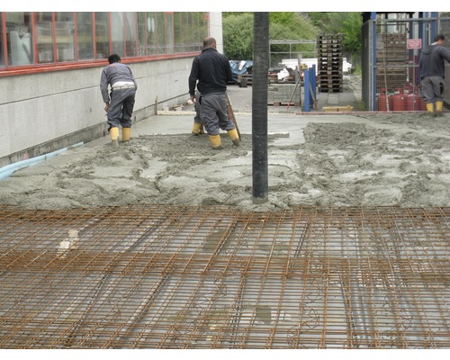 Travaux de bétonnage avec treillis d''armature et ouvriers du bâtiment.