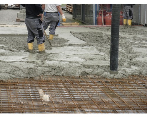 Travaux de bétonnage avec treillis d''armature et ouvriers du bâtiment.
