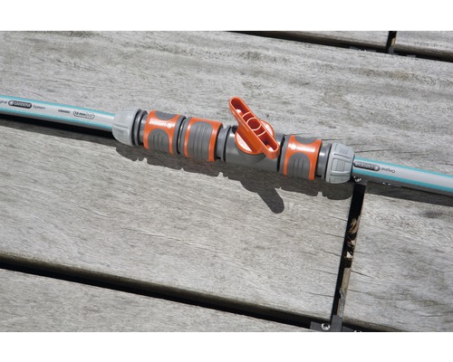 Vanne de régulation Gardena reliée à un tuyau d''arrosage sur une table en bois