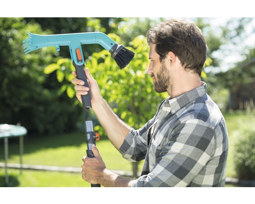 Un homme assemble une brosse de nettoyage télescopique pour le jardin
