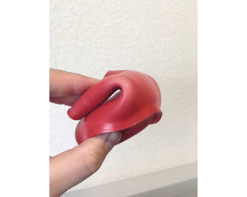 Un joint en caoutchouc rouge tenu par une main.