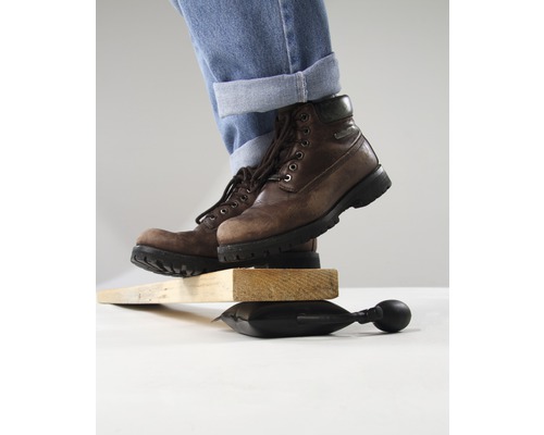 Person mit Stiefeln balanciert auf Luftkissen zwischen Holzstücken