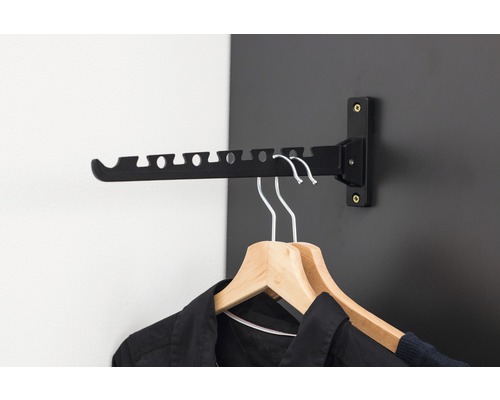 Wandgarderobe mit Kleiderbügeln und Kleidung an einer schwarzen Wand