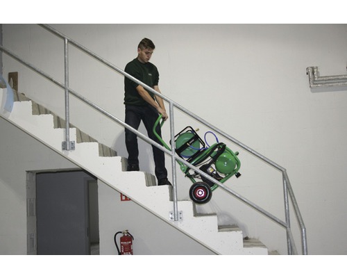 Une personne transporte un compresseur mobile dans un escalier.