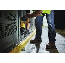 Un homme perce des trous dans un mur avec une perceuse.