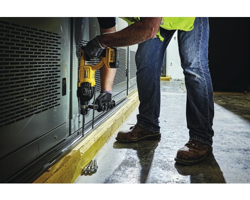 Un homme perce des trous dans un mur avec une perceuse.
