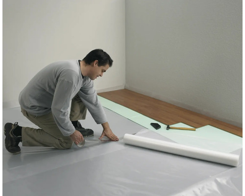 Homme posant un sol stratifié avec une sous-couche et des outils