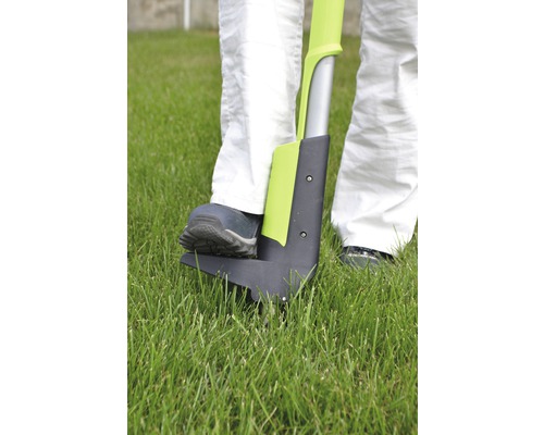 Person benutzt einen Unkrautstecher im Garten