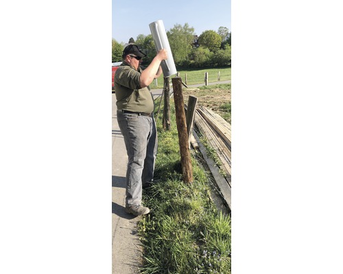 Une personne place un couvercle de poteau de clôture sur un poteau en bois à l''extérieur. Construction de clôtures.