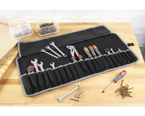 Sac à outils à rouler avec clés, tournevis, pinces et autres outils sur un établi