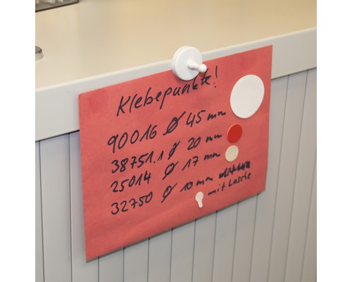 Ein rotes Blatt Papier mit Informationen zu Klebepunkten, befestigt mit einem weißen Magneten.