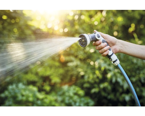 Eine Hand hält eine Gartenspritze, aus der Wasser austritt
