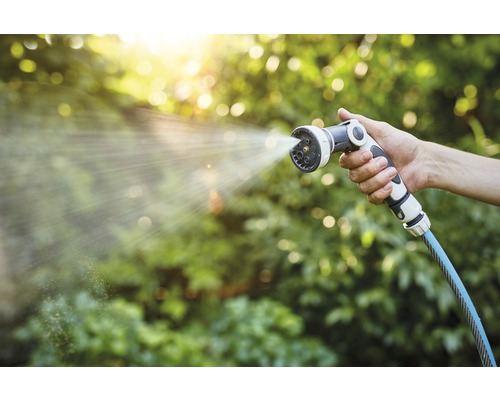 Eine Hand hält eine Gartenspritze, aus der Wasser kommt.