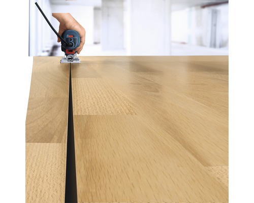 Une main guide une défonceuse le long d''un plan de travail en bois pour fraiser une rainure.