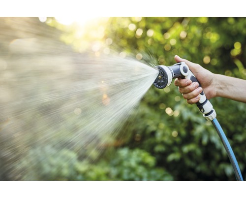 Hand hält Gartenschlauch mit Sprühkopf