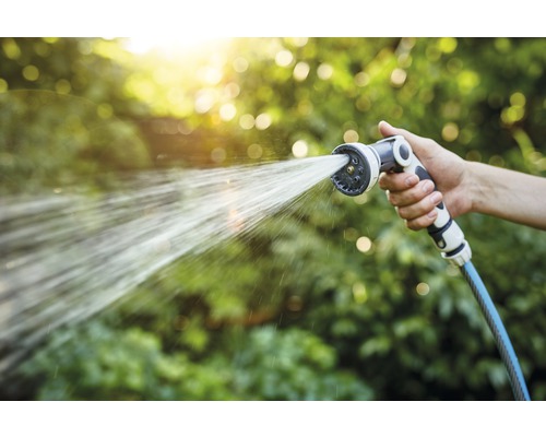 Hand hält Gartenschlauch mit Sprühkopf, der Wasser sprüht