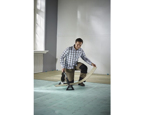 Un homme pose du stratifié avec un coupe-stratifié dans une pièce.