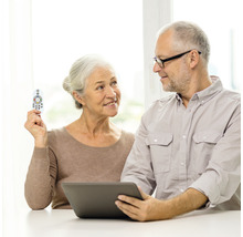 Couple âgé utilisant une tablette tactile avec une télécommande.