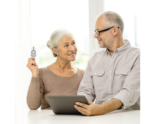 Couple âgé utilisant une tablette tactile avec une télécommande.