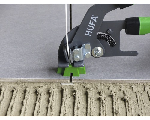 Outil de système de nivellement de carreaux en cours d''utilisation entre les carreaux et la colle à carrelage
