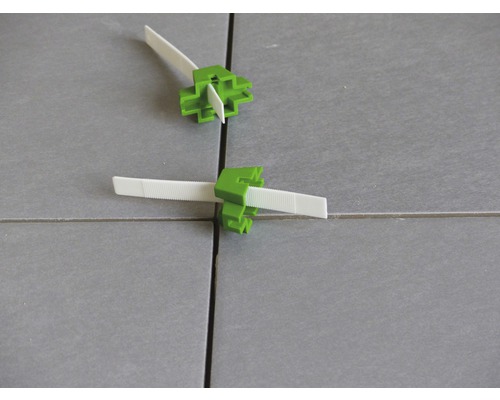 Système de nivellement de carreaux avec cales vertes et languettes de traction blanches sur carreaux
