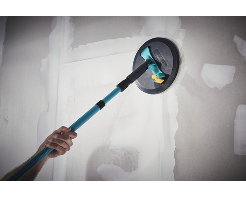 Une personne lisse un mur avec une ponceuse à plafond à manche télescopique.