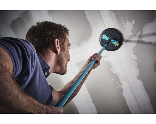 Un homme ponce un mur avec une ponceuse pour cloisons sèches