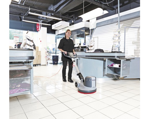 Frau reinigt Boden mit Reinigungsmaschine im Einzelhandel.