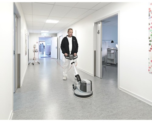 Eine Person reinigt einen Flur mit einer Reinigungsmaschine.