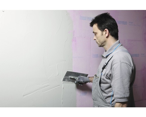 Un homme applique du plâtre sur un mur.