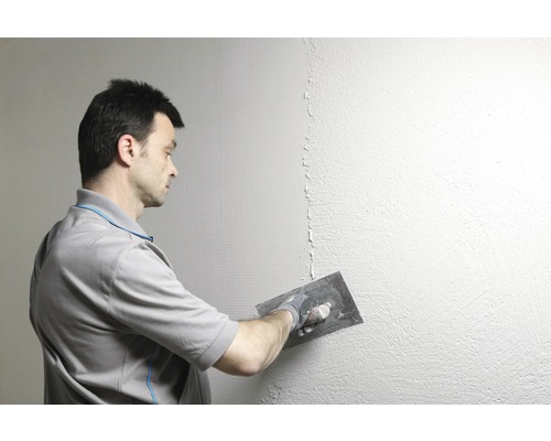 Homme lissant un mur avec une spatule