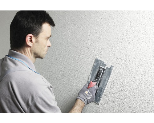 Homme enduisant un mur à la truelle