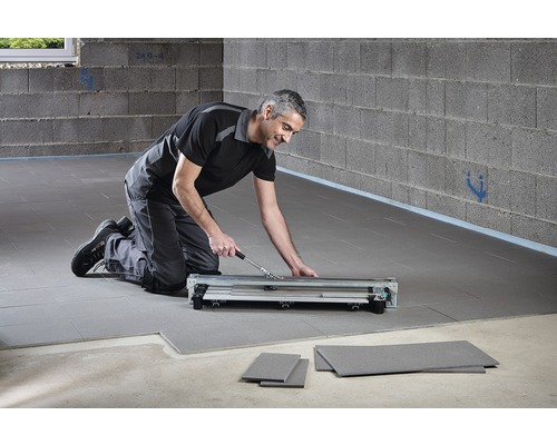 Un homme utilise un coupe-laminé pour la pose de stratifié.