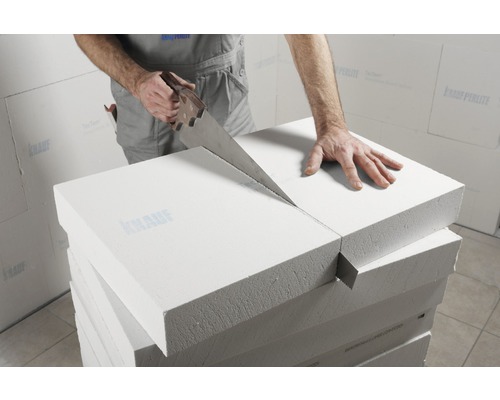 Ein Arbeiter sägt Porenbetonsteine mit einer Handsäge.