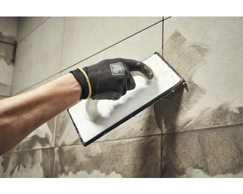 Carreleur appliquant du coulis sur des carreaux avec une taloche à joints