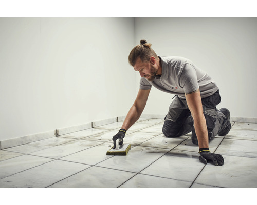 Carreleur nettoie les carreaux de sol avec une éponge