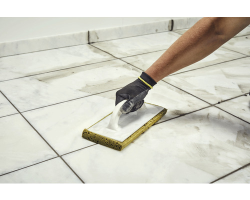 Carreleur nettoyant les carreaux avec une taloche éponge