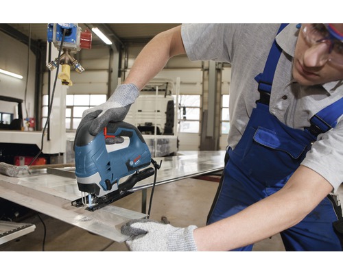 Eine Person benutzt eine Stichsäge, um ein Metallstück zu schneiden.