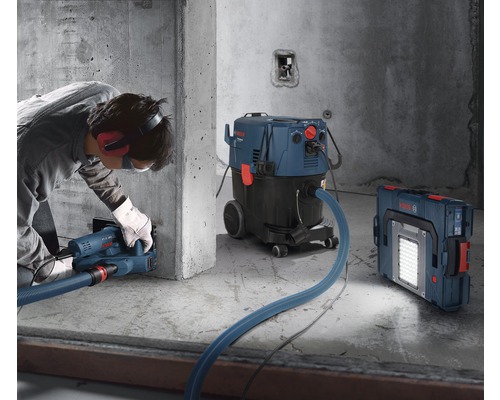 Scène d''application avec une rainureuse à murs, un aspirateur industriel et un projecteur de chantier sans fil sur un chantier