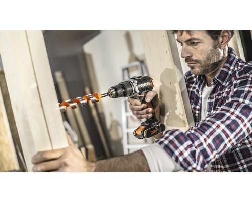 Un homme perce un trou dans une planche de bois avec une perceuse sans fil.