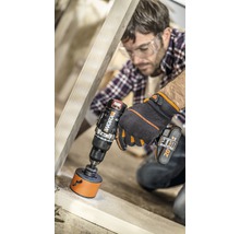 Un homme perce un trou dans un cadre en bois avec une perceuse-visseuse sans fil