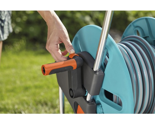 Eine Person bedient eine Schlauchtrommel zum Aufwickeln eines Gartenschlauchs.