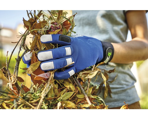 Une main gantée tenant des déchets de jardin.