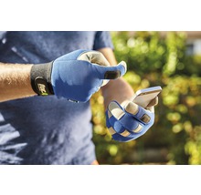 Une personne portant des gants de travail utilise un smartphone.